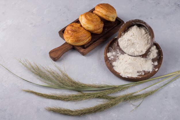 Kekse oder Brötchen mit Mehl auf einer Holzplatte mit Gewürzen serviert