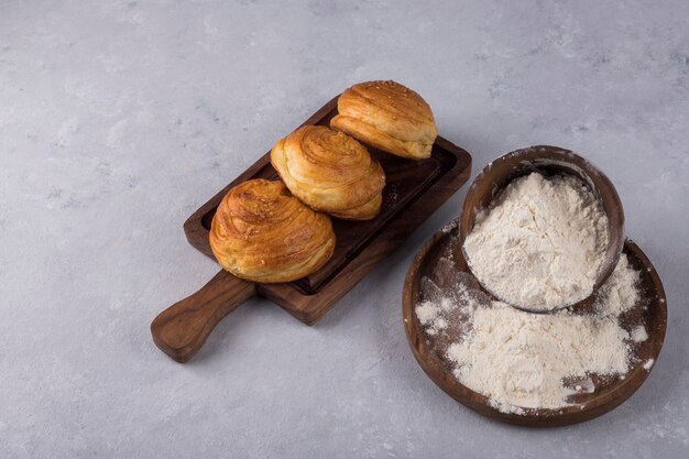 Kekse oder Brötchen mit Mehl auf einer Holzplatte