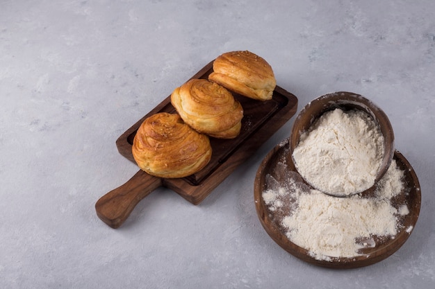 Kekse oder Brötchen mit Mehl auf einer Holzplatte