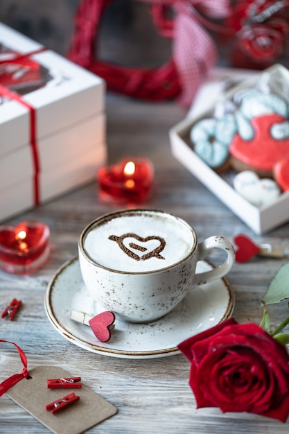 Kekse oder Lebkuchen in einer Geschenkbox mit einem roten Band auf einem Holztisch. Valentinstag.