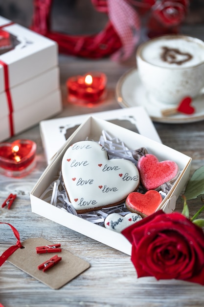 Kekse oder Lebkuchen in einer Geschenkbox mit einem roten Band auf einem Holztisch. Valentinstag.