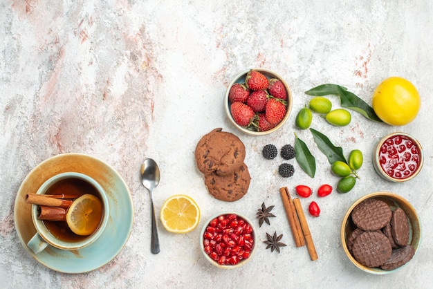 Kekse und Erdbeeren Granatapfel Sternanis Kekse Erdbeeren eine Tasse Tee Zitrusfrüchte Zimtstangen Gabel auf dem Tisch