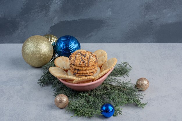 Kekse und Kekse in einer Schüssel inmitten von Weihnachtsschmuck auf Marmoroberfläche