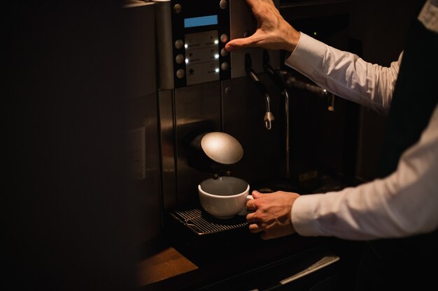 Kellner macht eine Tasse Kaffee aus der Espressomaschine