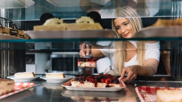 Kostenloses Foto kellnerin, die beerenschwammkuchen hält