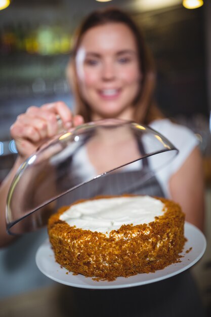 Kellnerin hält einen Teller mit Kuchen