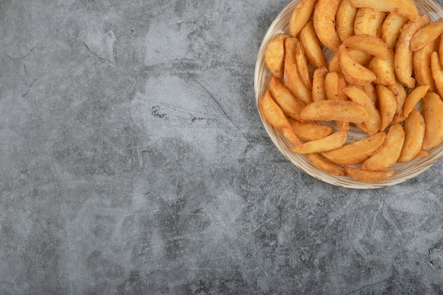 Keramikplatte der leckeren gebratenen kartoffelschnitze auf steinhintergrund.