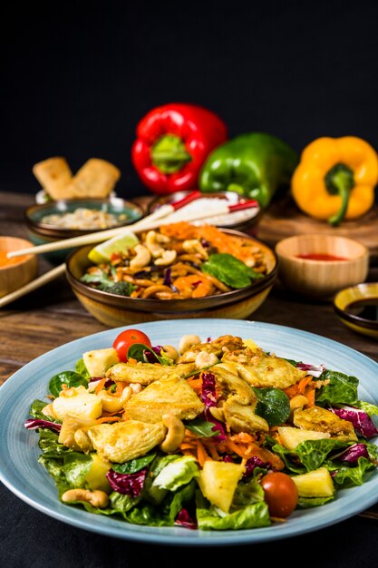 Keramikplatte des Hühnersalats mit Nudeln auf Schreibtisch