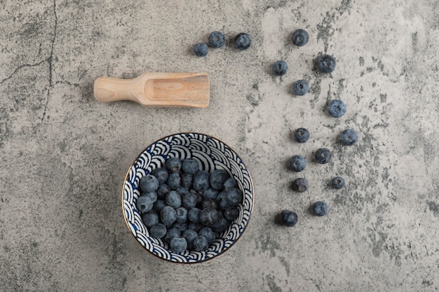 Keramikschale mit leckeren frischen Blaubeeren auf Marmoroberfläche