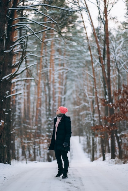 Kerl, der auf der Straße mitten im Wald steht, umgeben von Schnee
