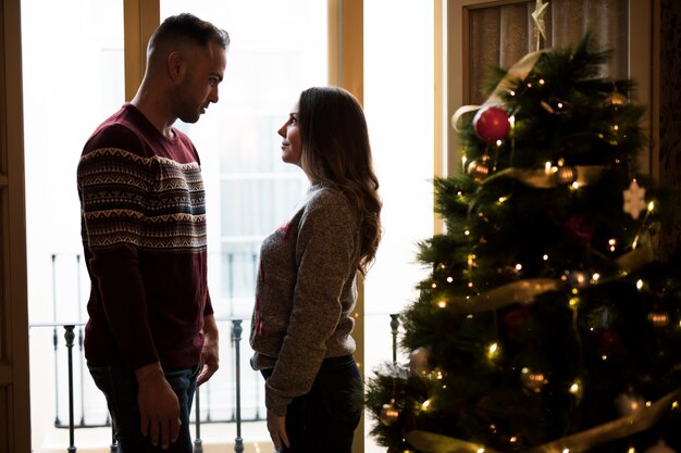 Kerl, der Dame nahe Weihnachtsbaum betrachtet