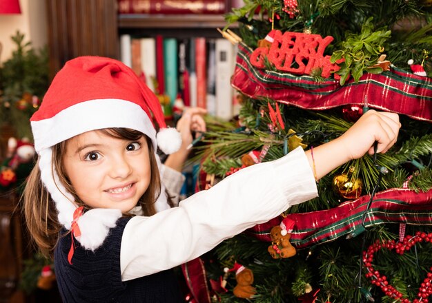 Kid schmücken einen Baum auf Weihnachten