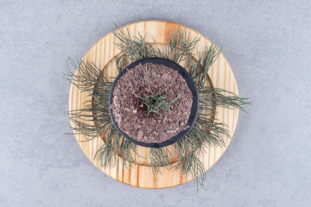 Kiefernblätter und ein Kuchen auf einer Holzplatte auf Marmortisch.