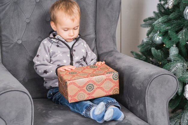 Kind auf der Couch mit Geschenkbox