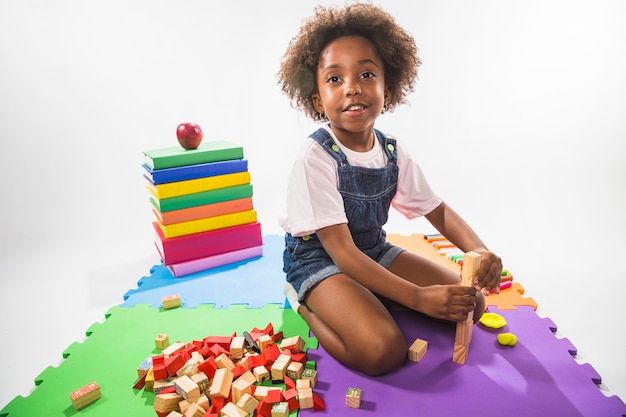 Kostenloses Foto kind beim spielen mit würfeln auf spielteppich im studio