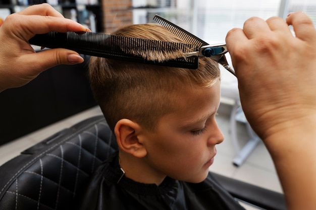 Kostenloses Foto kind bekommt haarschnitt im hohen winkel des salons