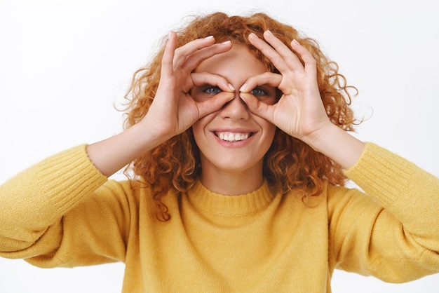 Kostenloses Foto kind bleiben, egal in welchem alter sie sind fröhliche, verspielte, niedliche, rothaarige, dumme frau mit lockigem haar, die mit den fingern eine brille macht und durch den spaß lächelt, freudig weißer hintergrund