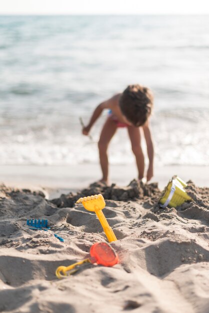 Kind, das am Strand mit Spielwaren spielt