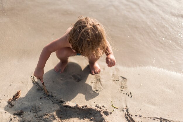 Kind, das am Strand von oben spielt