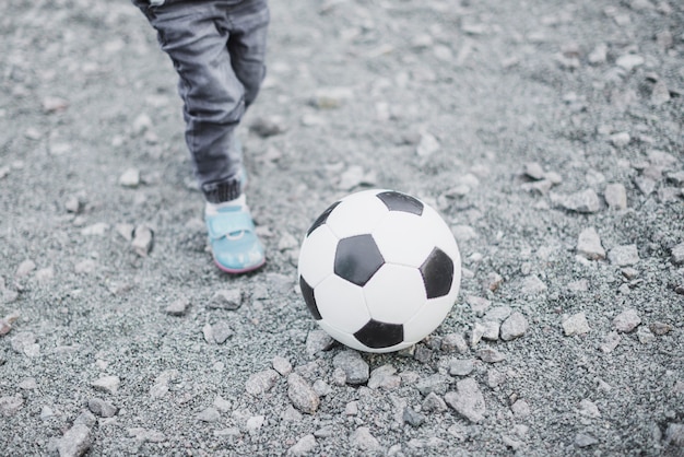 Kind, das draußen mit Fußball spielt