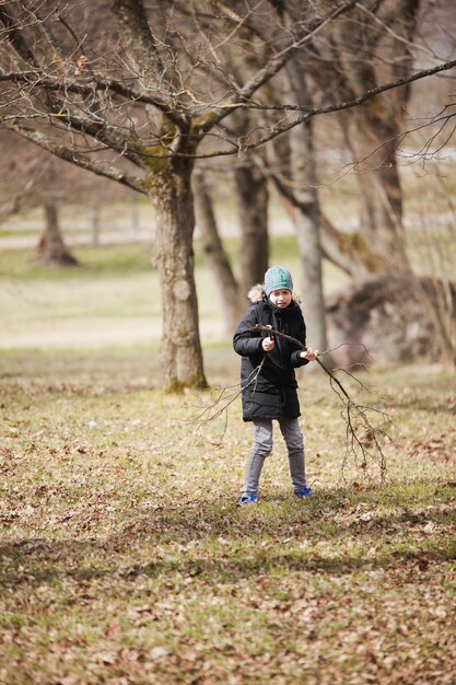 Kind, das einen Zweig im Park nimmt