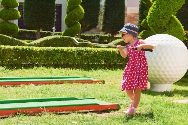 Kostenloses Foto kind, das minigolf auf kunstrasen spielt.