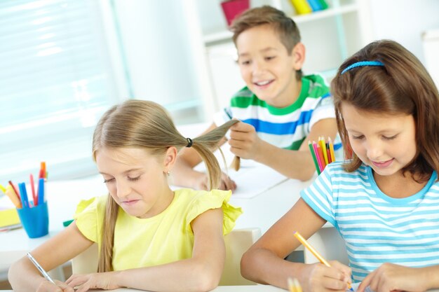 Kind, das mit dem Haar seiner Mitschüler spielen