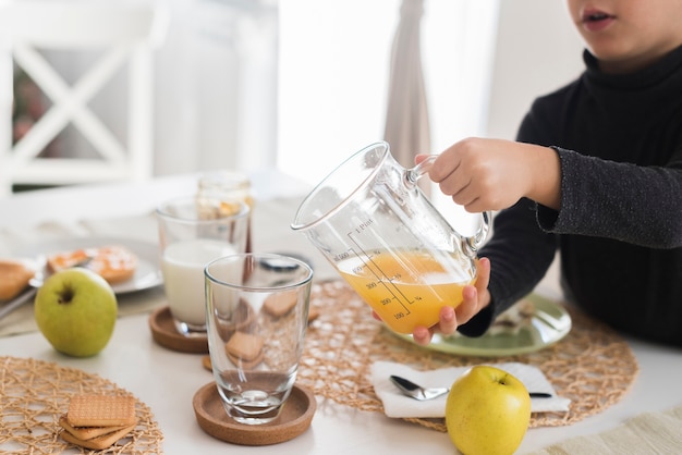 Kind, das Orangensaft im Glas gießt