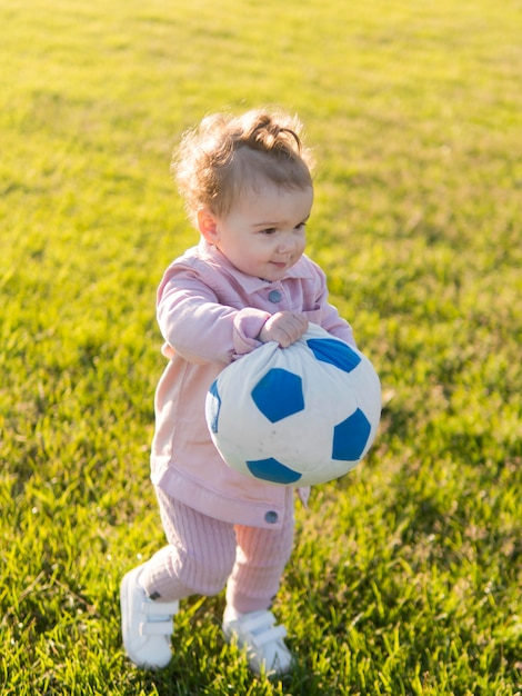 Kostenloses Foto kind, das rosa kleidung spielt mit ball spielt