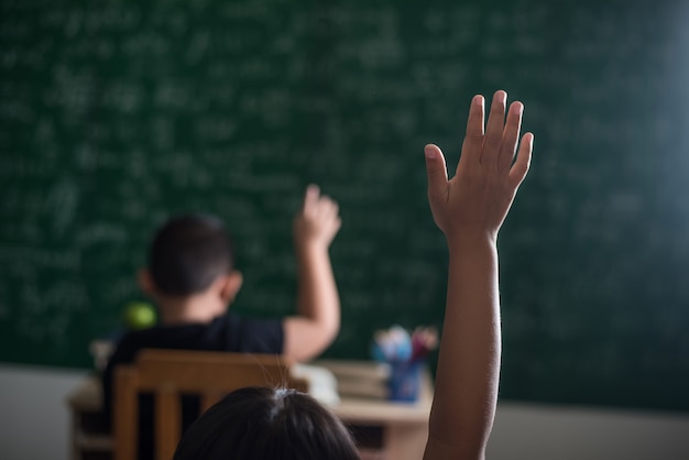 Kostenloses Foto kind, das seine hand im klassenzimmer anhebt