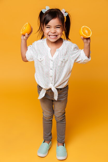Kind des kleinen Mädchens, das Orange hält.
