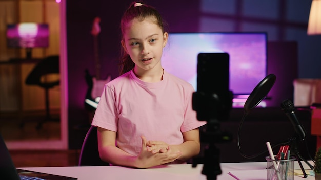 Kind filmt mit Smartphone auf Stativstabilisator im blau neonbeleuchteten Wohnzimmer