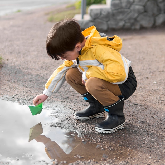 Kind im Regenmantel, der im Wasser spielt