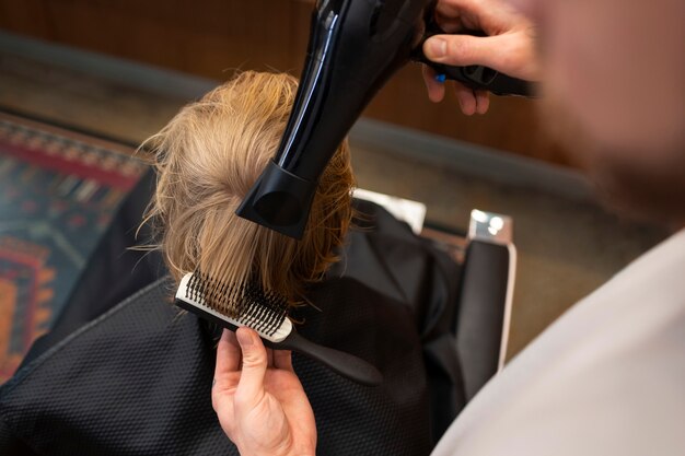 Kind lässt sich im Salon die Haare föhnen