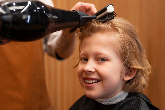 Kind lässt sich im Salon die Haare föhnen