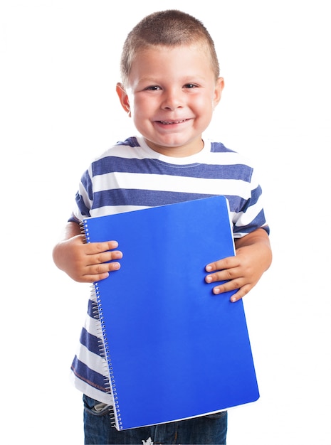 Kind mit einem blauen Notizbuch lächelnd