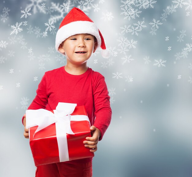 Kind mit einem roten Geschenk in einem Schneeflocken-Hintergrund