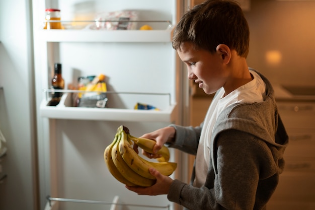 Kostenloses Foto kind mit mittlerem schuss, das bananen hält