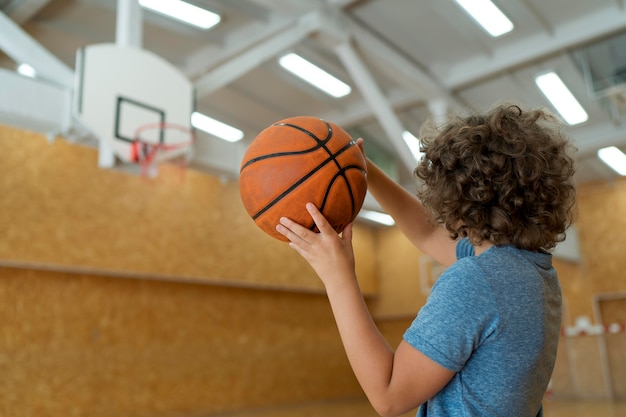 Kind mit mittlerem Schuss, das Basketball hält