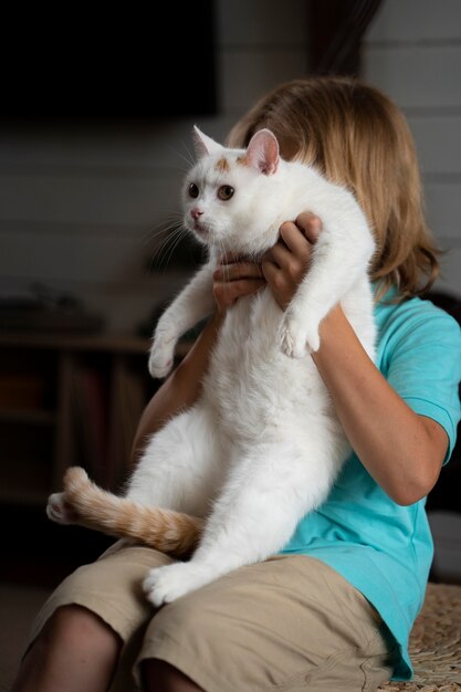 Kind mit mittlerem Schuss, das Katze hält