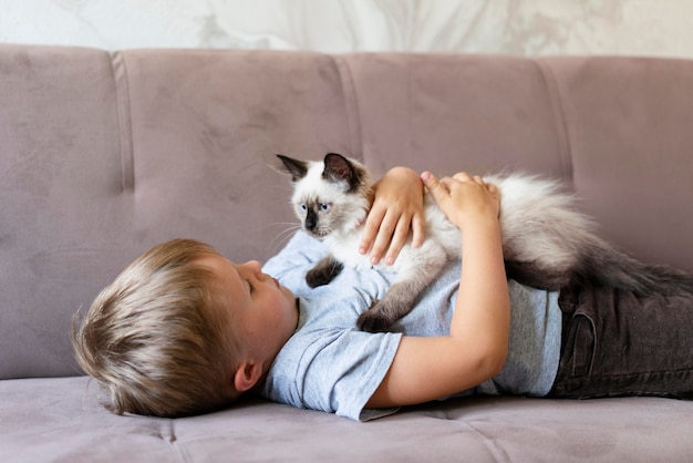 Kind mit mittlerem Schuss, das süße Katze hält