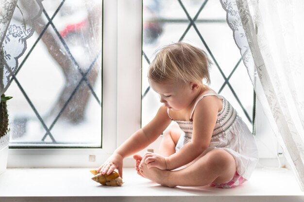 Kind spielt mit großer Schnecke am Fenster Real Interior Lifestyle Softfokus das Konzept der Kindheit und Tiere