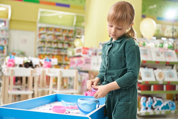 Kostenloses Foto kind spielt mit kleinem sandkasten und satz spielzeug im laden.