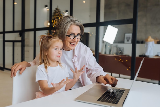 Kind und Oma schauen mit Laptop in die Kamera