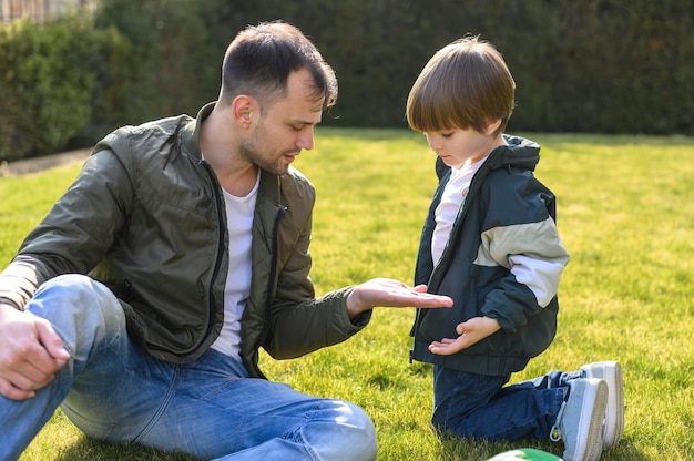 Kind und Vater sitzen auf Gras