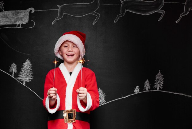 Kind verkleidet als Weihnachtsmann, der eine Wunderkerze genießt