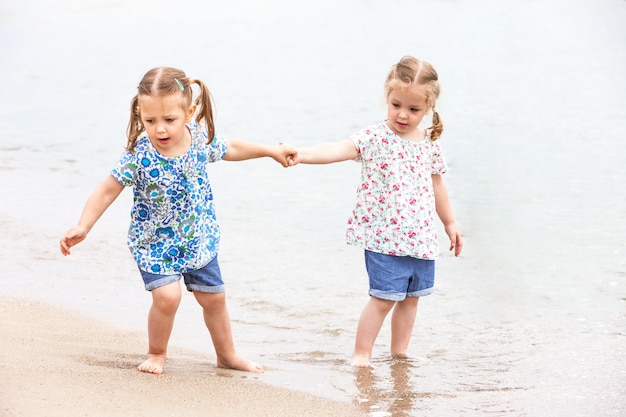 Kinder am Meeresstrand. Zwillinge gehen am Meerwasser entlang.