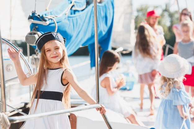 Kinder an Bord der Seelyacht. Teenager oder Kind Mädchen im Freien. Farbenfrohe Kleider. Kindermode, sonnige Sommer-, Fluss- und Ferienkonzepte.