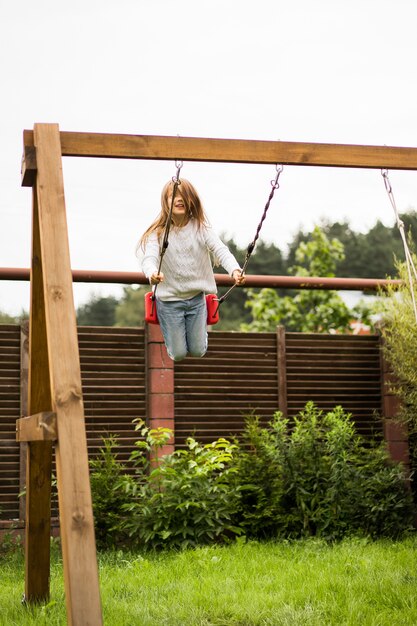 Kinder auf der Schaukel. Mädchen schwingt auf einer Schaukel im Hof. Sommerspaß.