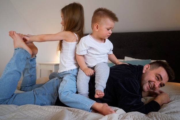 Kinder bringen ihren Vater zum Lachen, indem sie ihn kitzeln